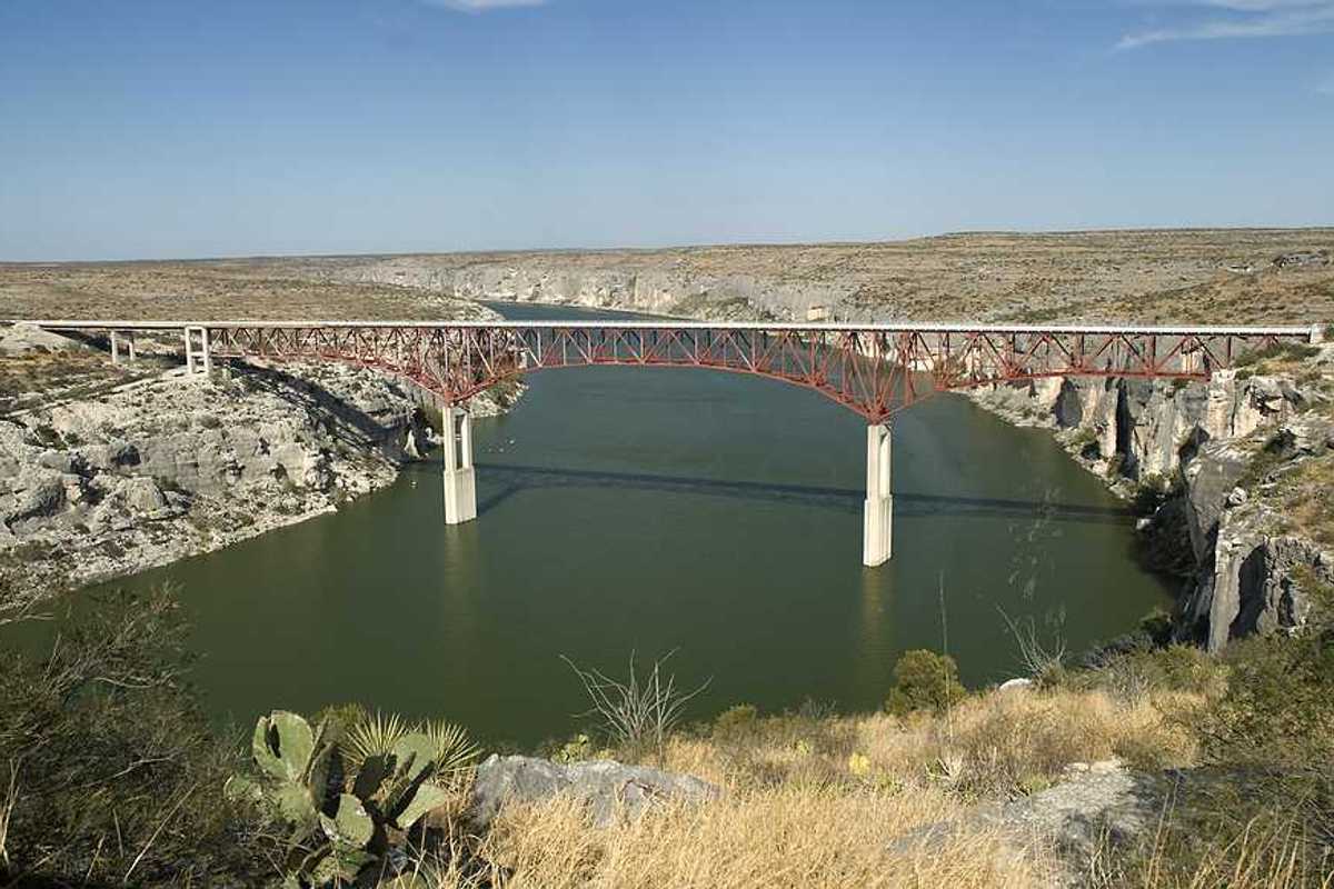 A view of a river flowing under a bridge in a dry landscape