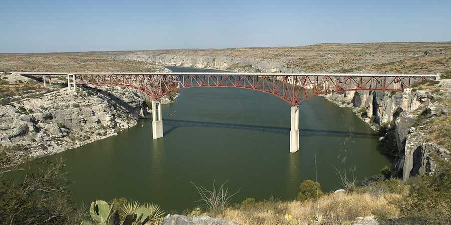 A view of a river flowing under a bridge in a dry landscape