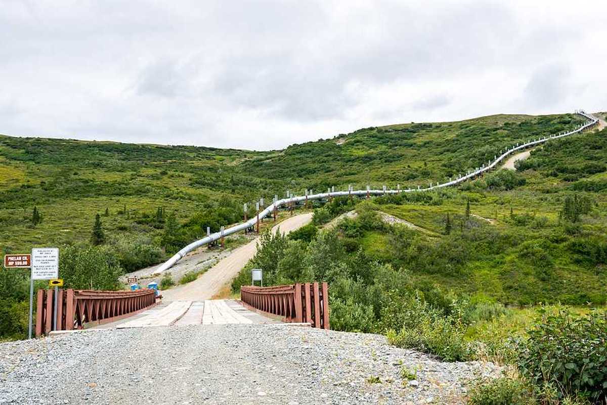 A view of a road in Alaska with an oil pipeline alongside it