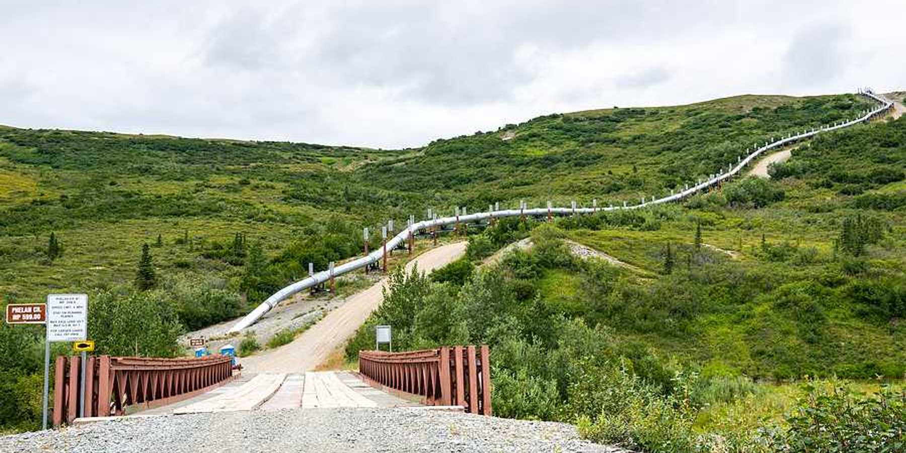 A view of a road in Alaska with an oil pipeline alongside it
