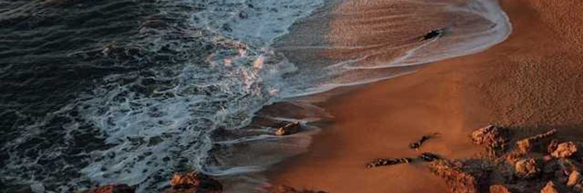 A view of a rocky beach from above with waves crashing on the shore