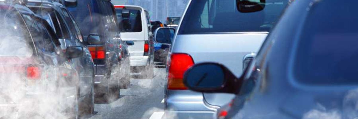 A view of a row of cars in traffic with car exhaust