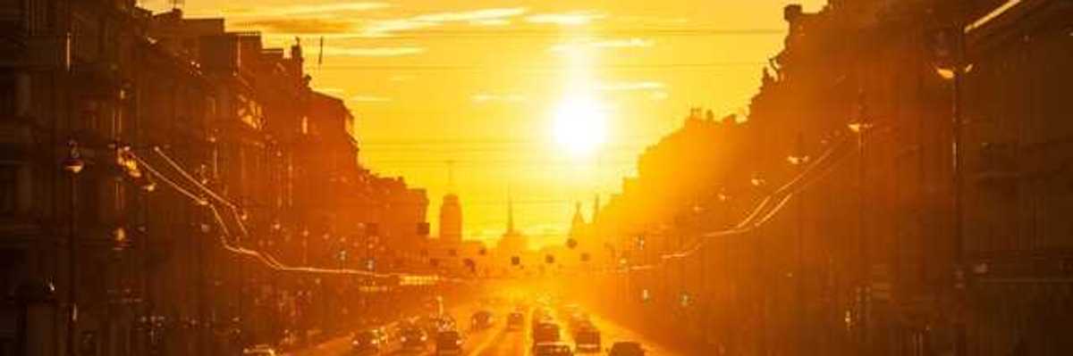 A view of a street in a European city with the setting sun in the background