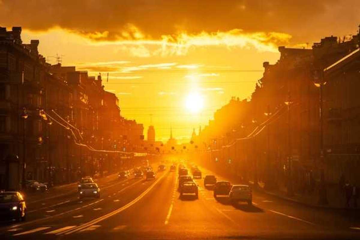 A view of a street in a European city with the setting sun in the background