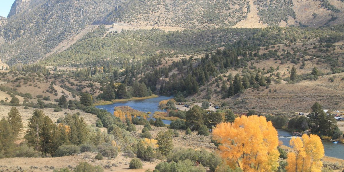 a view of a valley with a river and mountains in the background.