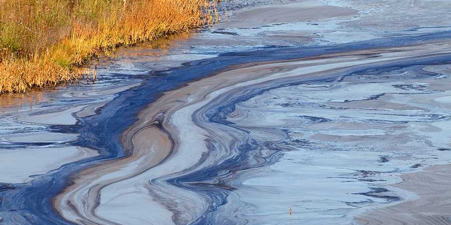 A view of a water source with oil slick on the top