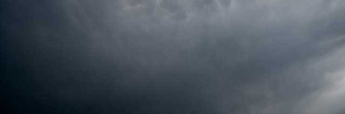 A view of dark storm clouds with blue skies in the background