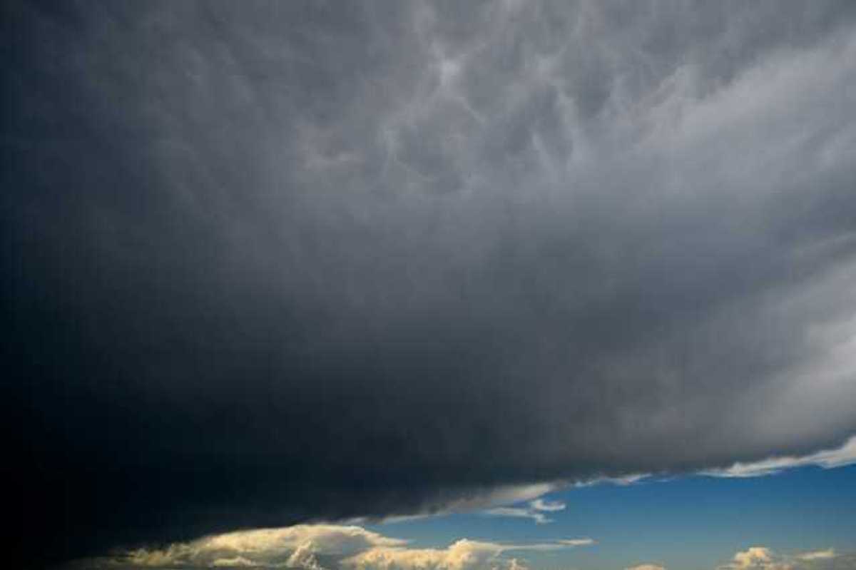 A view of dark storm clouds with blue skies in the background