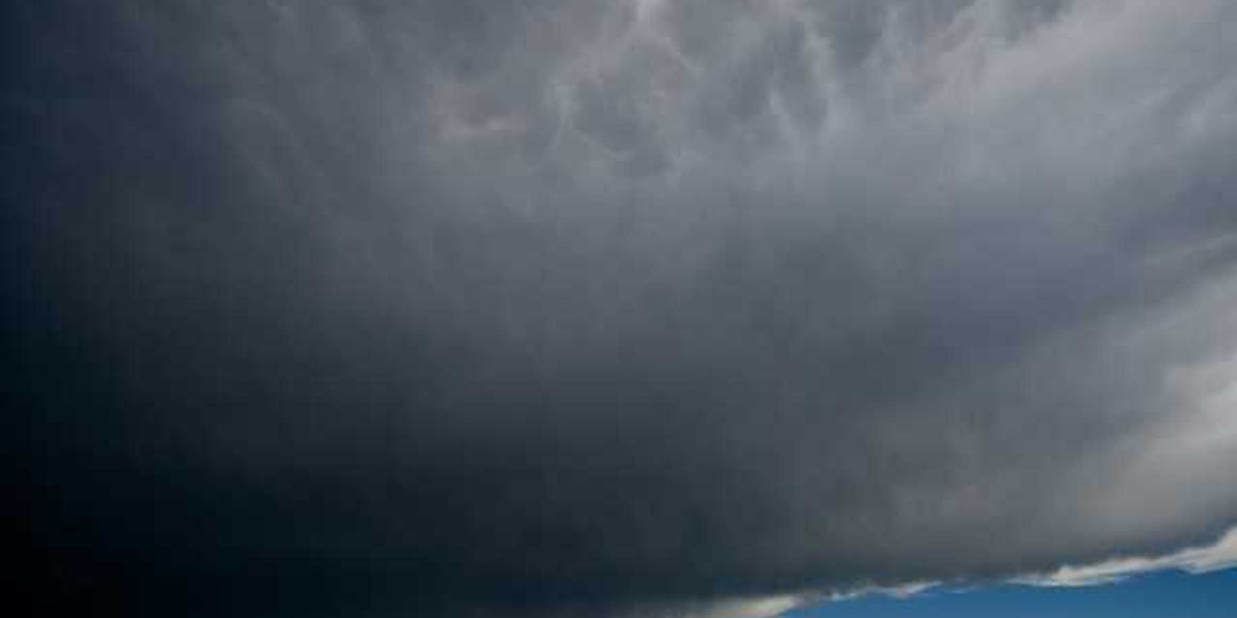 A view of dark storm clouds with blue skies in the background