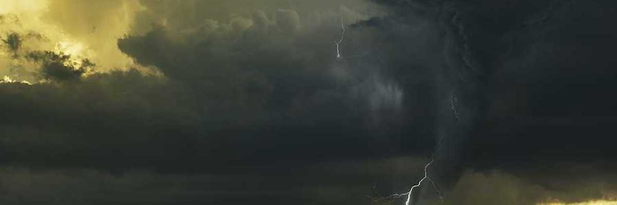 A view of dark storm clouds with lightning and a tornado forming