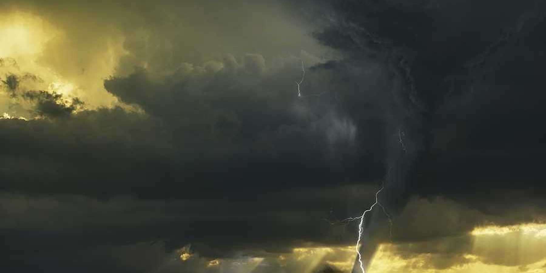 A view of dark storm clouds with lightning and a tornado forming