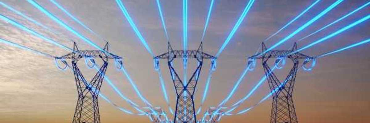 A view of electricity towers with blue wires stretching into the distance against a red sky during sunset