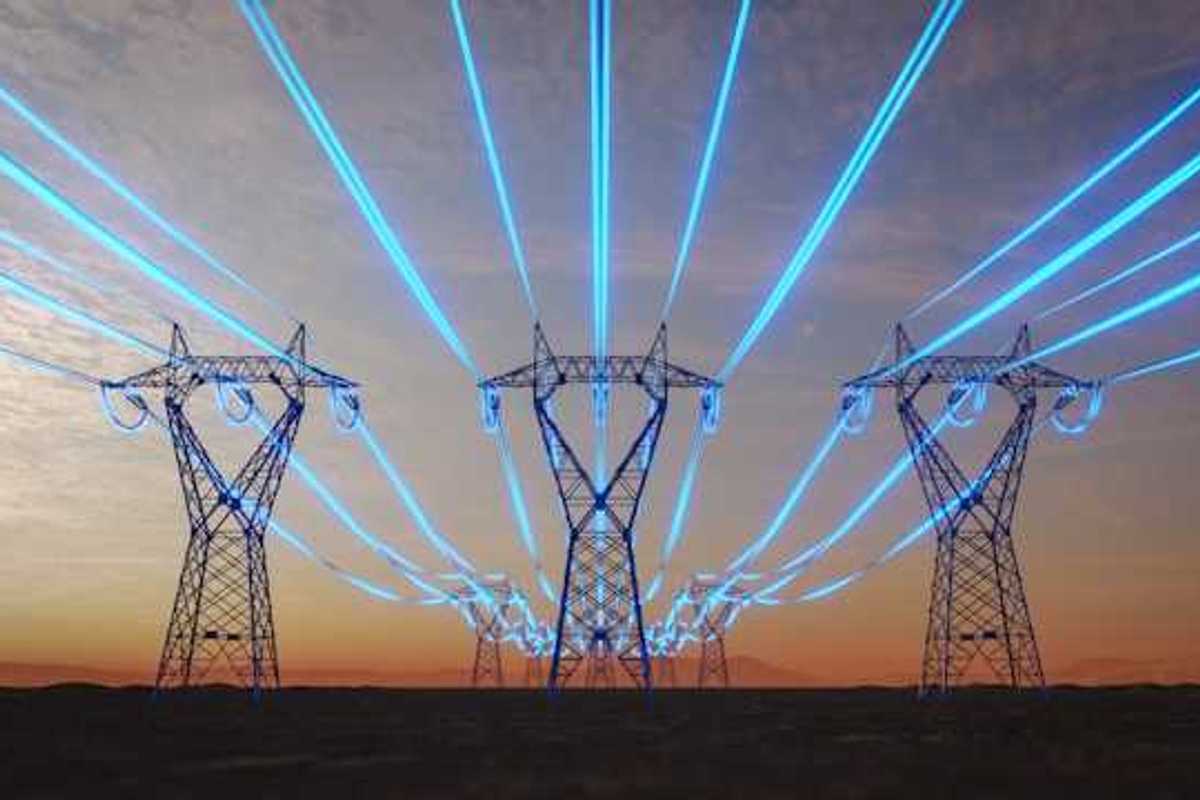 A view of electricity towers with blue wires stretching into the distance against a red sky during sunset