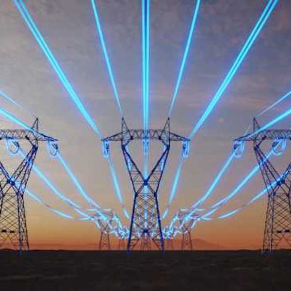 A view of electricity towers with blue wires stretching into the distance against a red sky during sunset