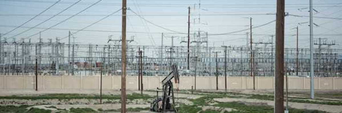 A view of energy lines with a small oil pump jack in a sandy field