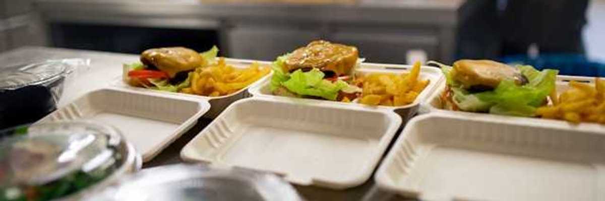A view of food containers in a kitchen filled with burgers, fries and salad