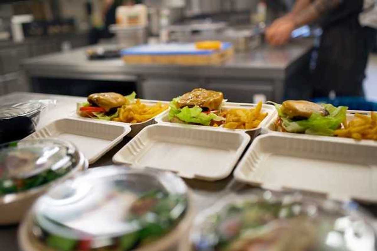 A view of food containers in a kitchen filled with burgers, fries and salad