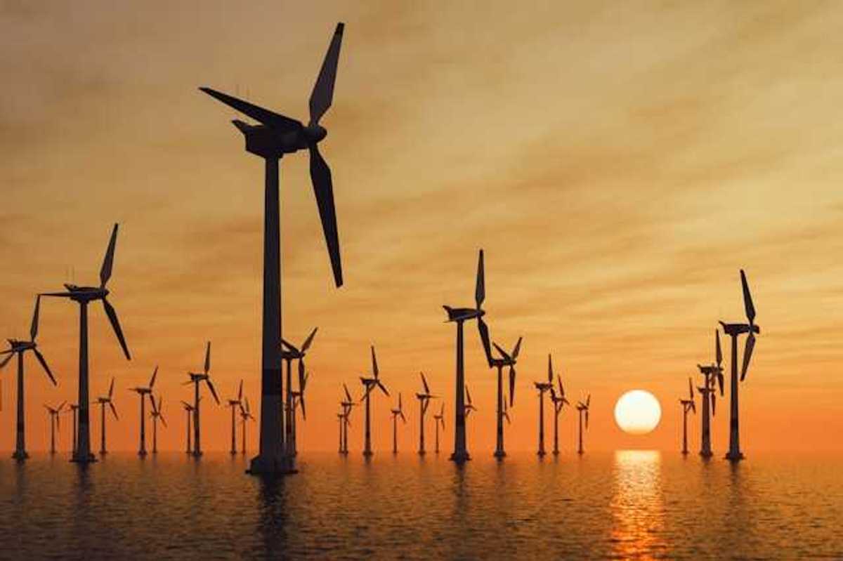 A view of many offshore wind turbines with the setting sun in the distance
