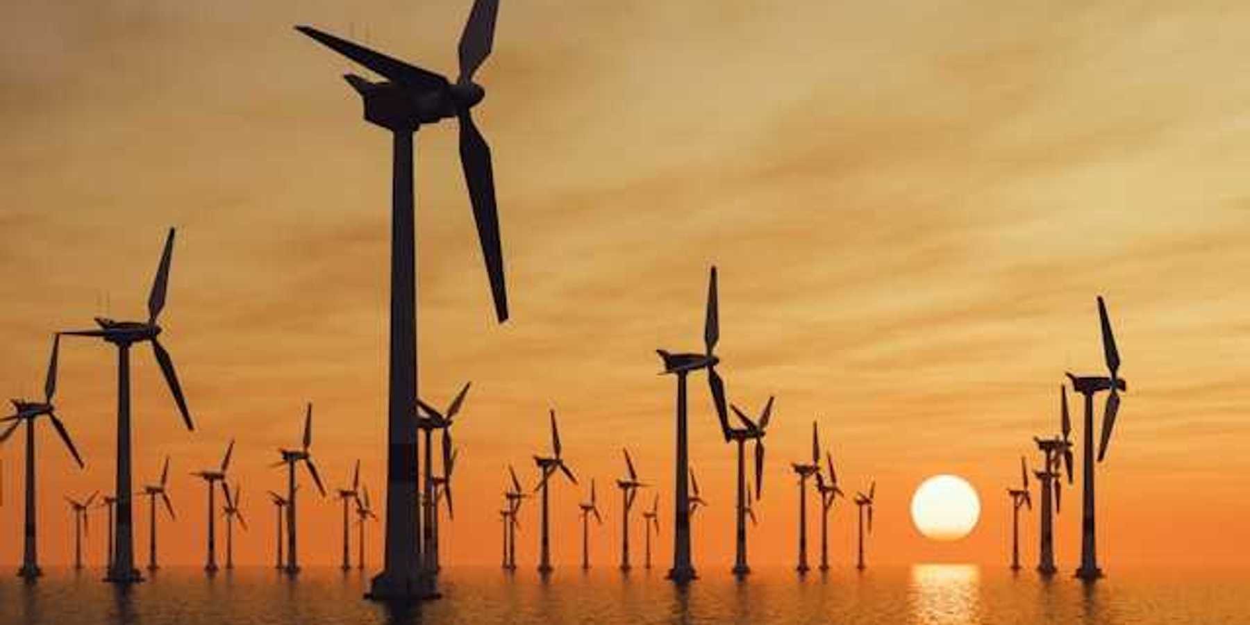 A view of many offshore wind turbines with the setting sun in the distance