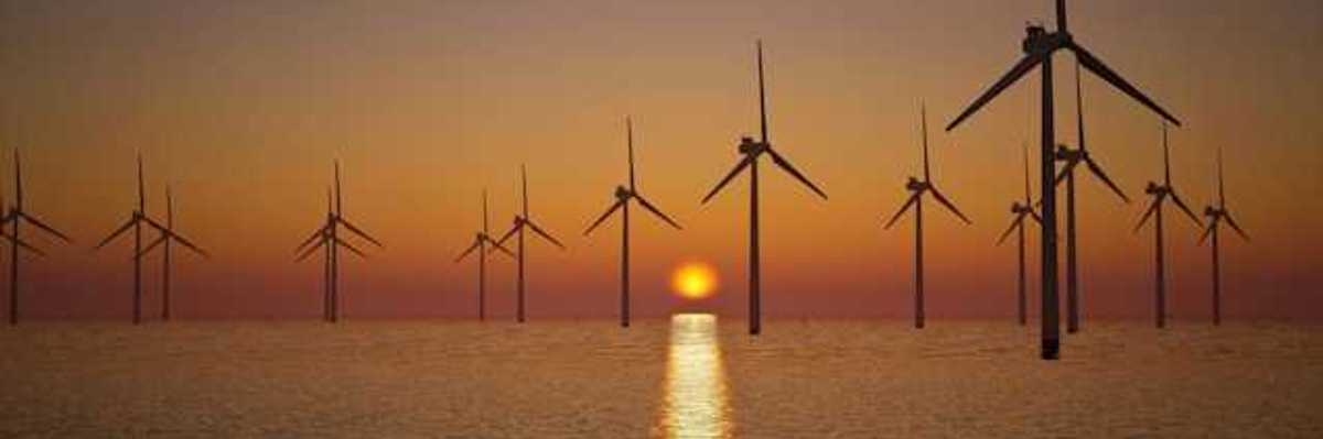 A view of offshore wind turbines with the setting sun in the distance