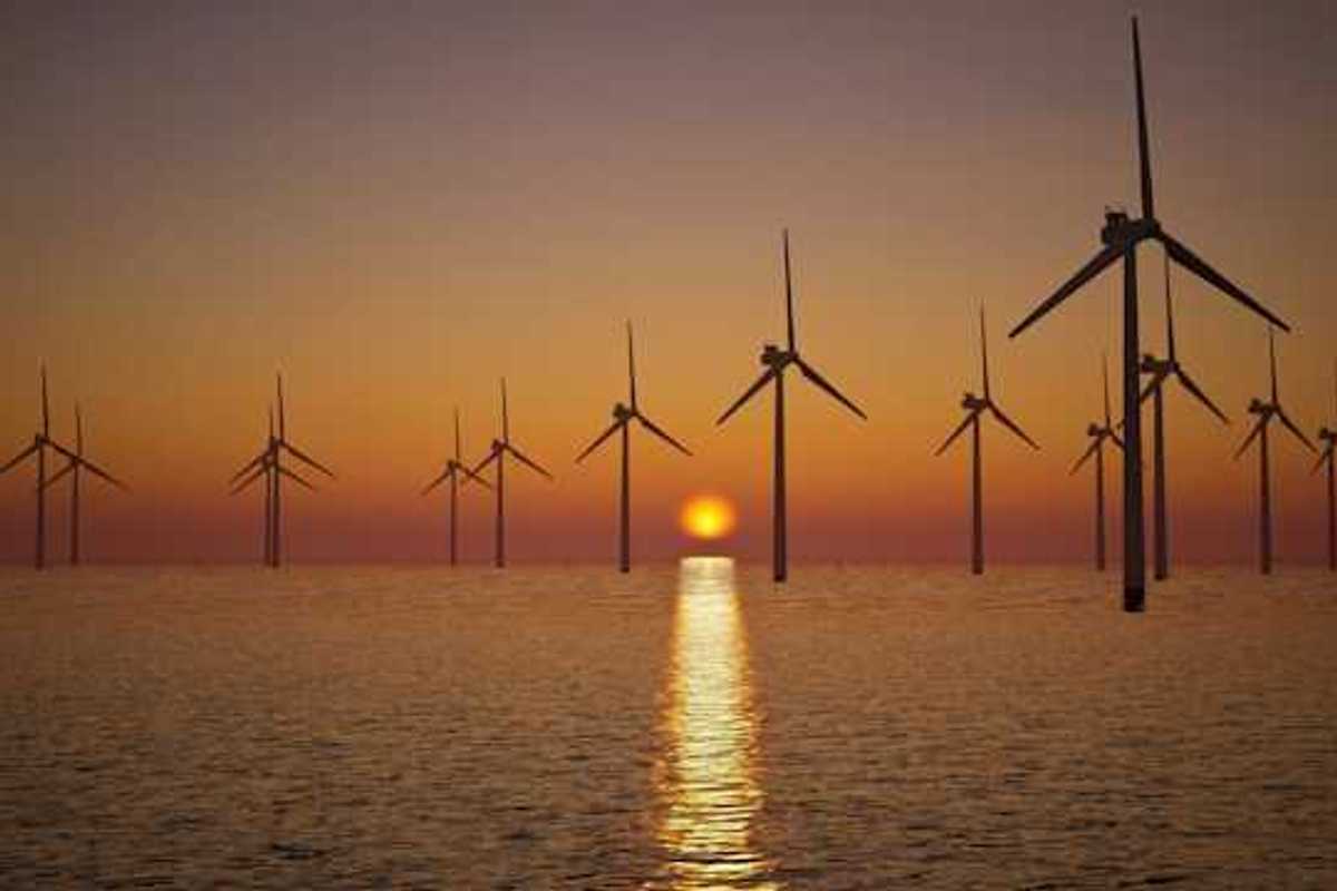 A view of offshore wind turbines with the setting sun in the distance