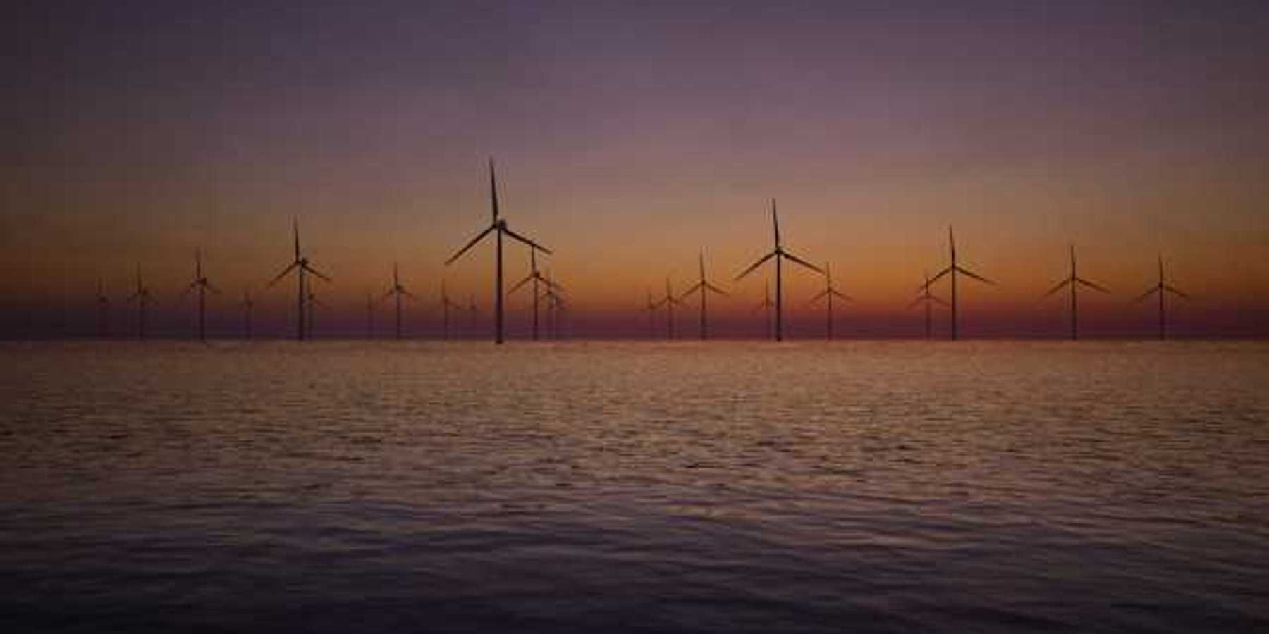 A view of offshore wind turbines with the sunset in the background