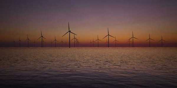 A view of offshore wind turbines with the sunset in the background