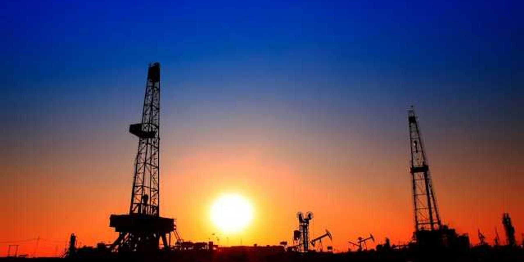 A view of oil pumps and flaring towers at sunset