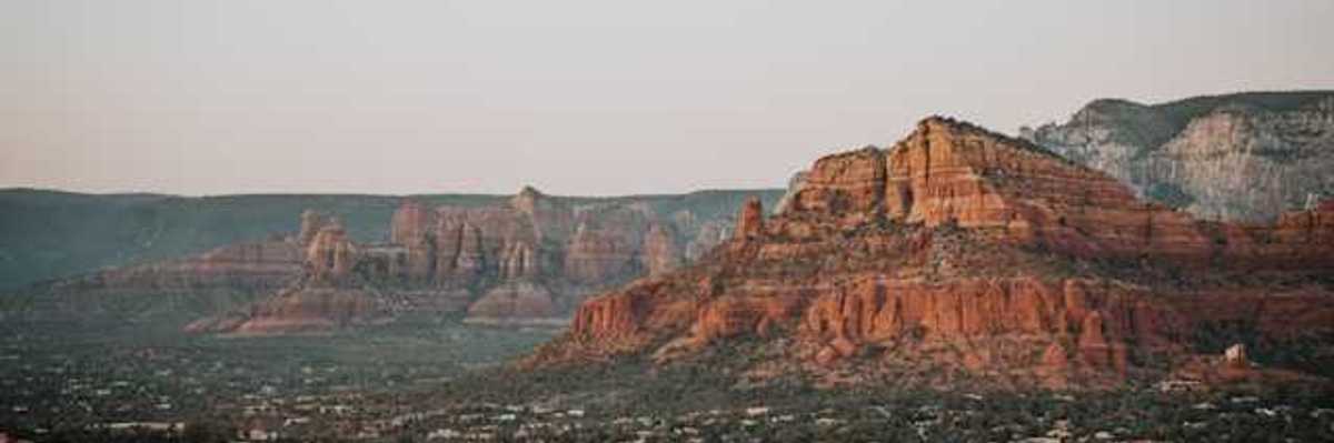 A view of red buttes with a town on the plain below them