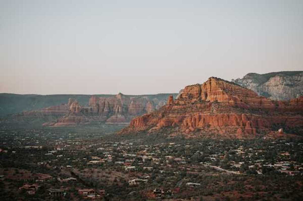 A view of red buttes with a town on the plain below them