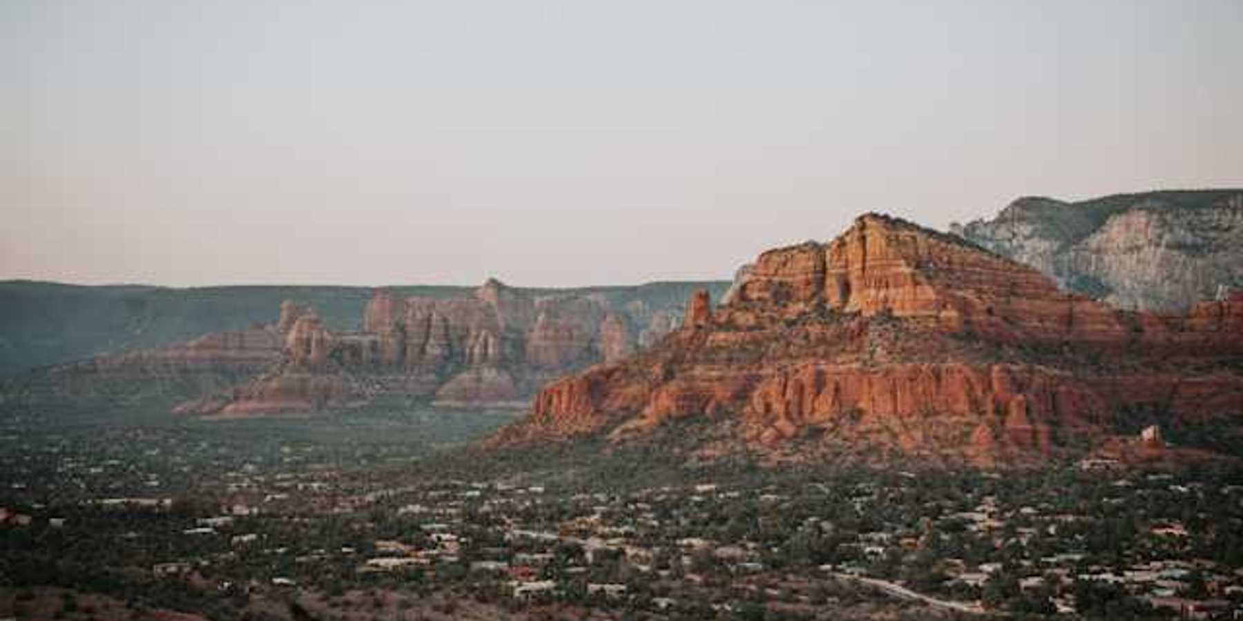 A view of red buttes with a town on the plain below them