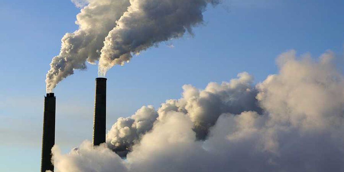 A view of smokestacks spewing smoke into a blue sky