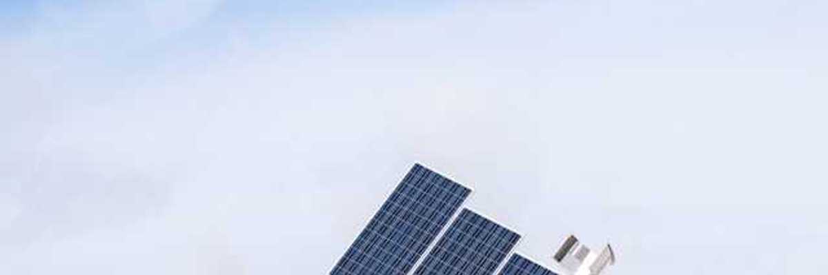 A view of solar panels with snow-covered hills behind them