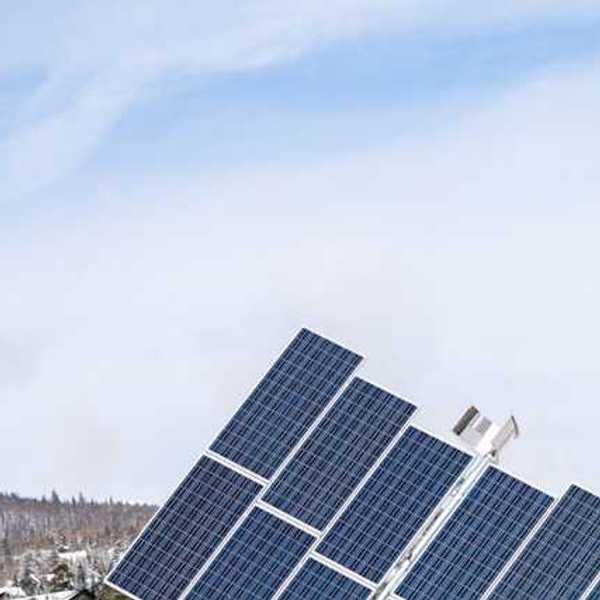 A view of solar panels with snow-covered hills behind them