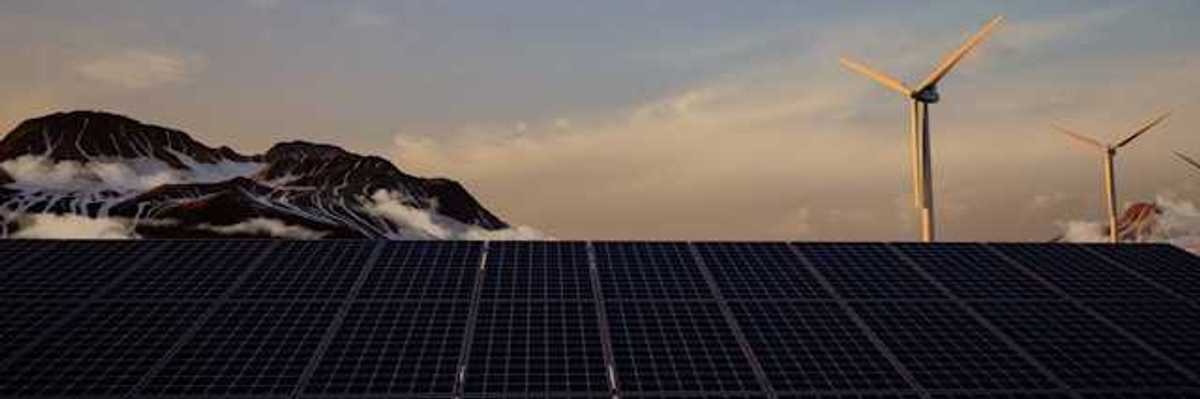 A view of solar panels with wind turbines and mountains in the background