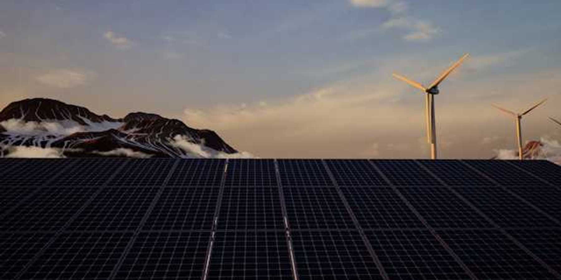 A view of solar panels with wind turbines and mountains in the background