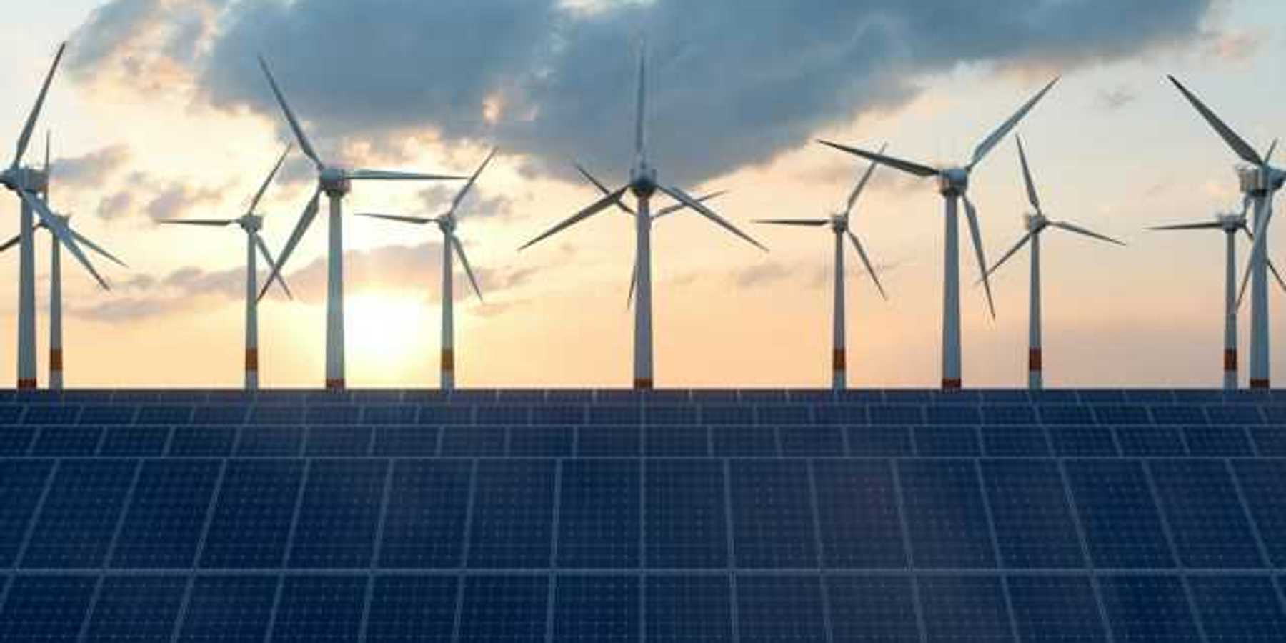 A view of solar panels with wind turbines in the background