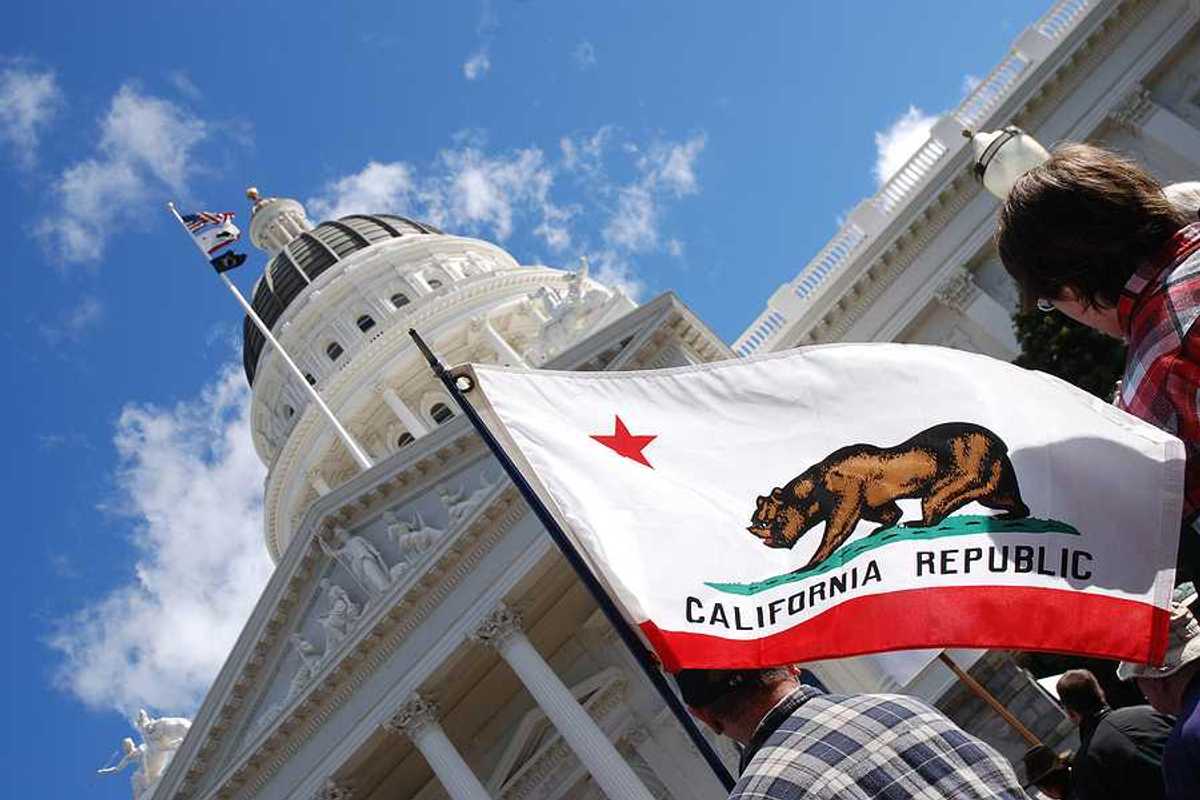 A view of the California flag flying next to the California capitol building
