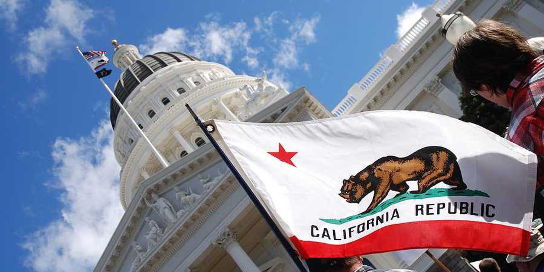 A view of the California flag flying next to the California capitol building