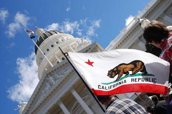 A view of the California flag flying next to the California capitol building