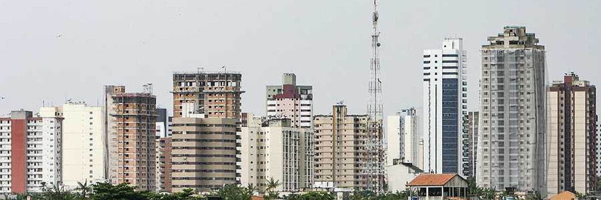 A view of the city of Belem in Brazil with huts by the ocean and skyscrapers in teh background