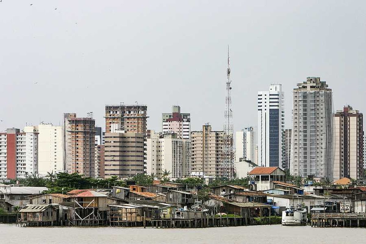 A view of the city of Belem in Brazil with huts by the ocean and skyscrapers in teh background