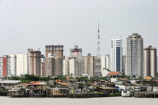 A view of the city of Belem in Brazil with huts by the ocean and skyscrapers in teh background