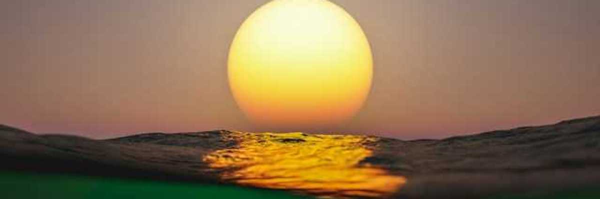 A view of the setting sun with ocean water in the foreground