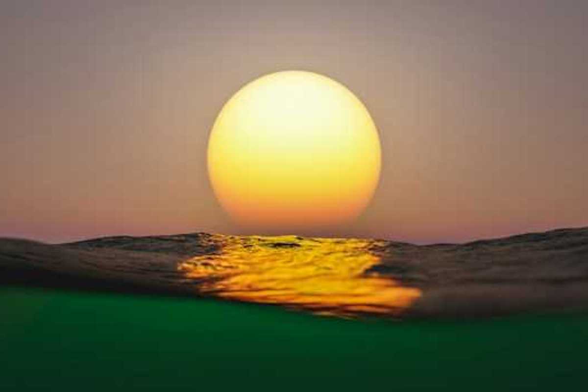 A view of the setting sun with ocean water in the foreground