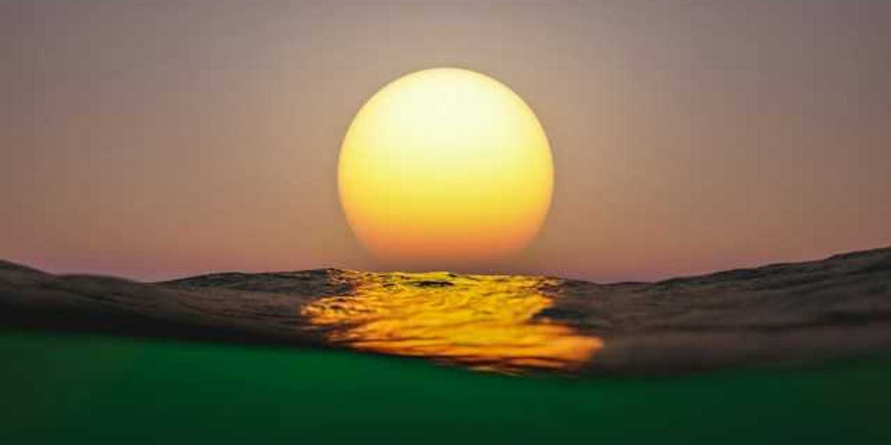 A view of the setting sun with ocean water in the foreground
