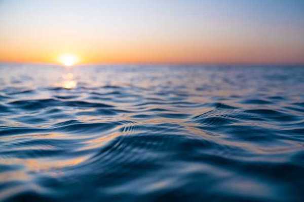 A view of the surface of the sea with the setting sun in the distance