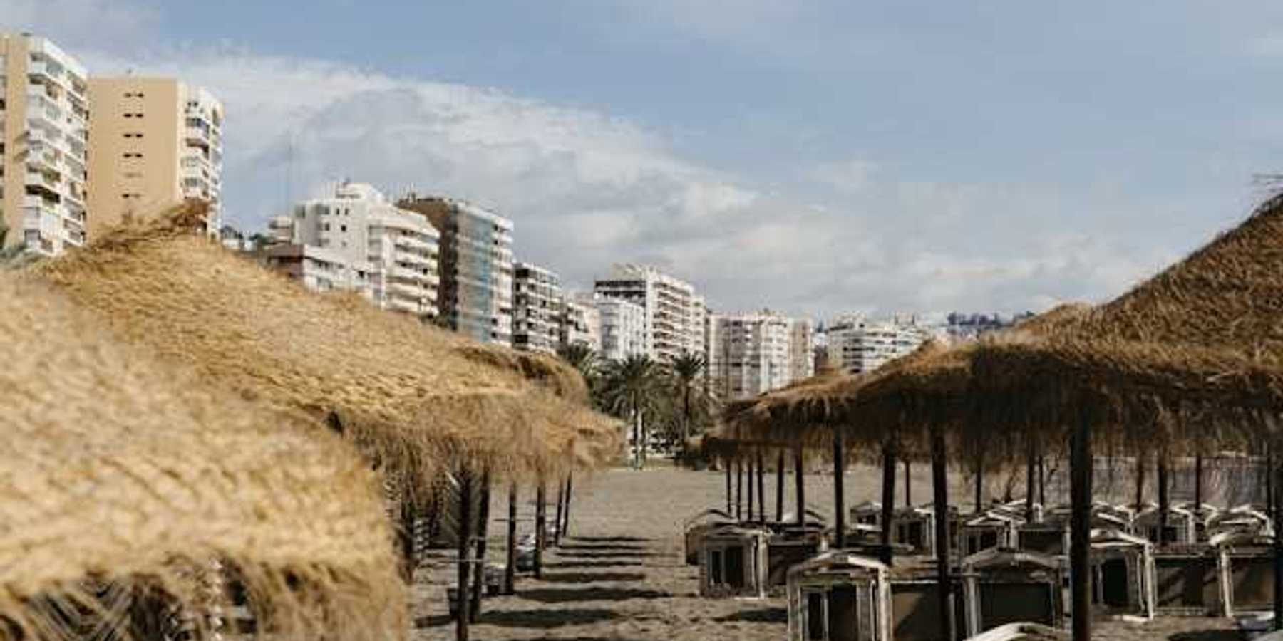 A view of umbrellas on a sandy beach with buildings in the background