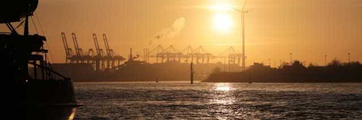 A view of water and ships at sunset with a wind turbine in the background