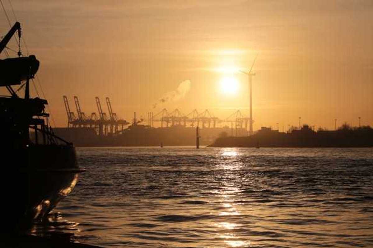 A view of water and ships at sunset with a wind turbine in the background